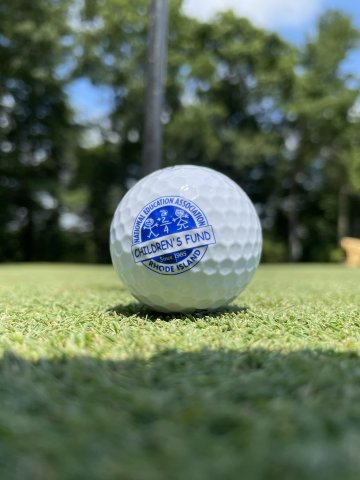 A Children's Fund golf ball sits on the green.